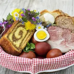 Co się daje do koszyczka wielkanocnego? Widać tu babkę, jajka, chleb, wędlinę i kwiaty.