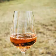 Un bicchiere di passito di Pantelleria, con il suo colore ambrato e le bollicine che danzano, pronto per essere gustato all'aperto.