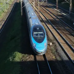 Błękitny pociąg Pendolino EIP mknie po torach.