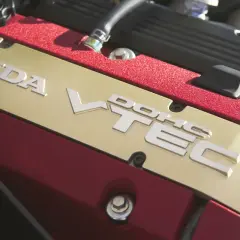 Złota pokrywa silnika Honda z napisem VTEC i czerwonymi akcentami.