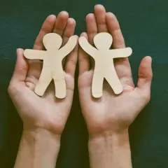 Dwie drewniane postacie ludzi w dłoniach. To symbol tego, co to jest przyjaźń krótko: wsparcie, bliskość i wspólne chwile.