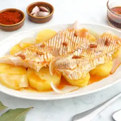 Raya a la gallega servida con patatas y cebolla, aderezada con aceite, pimentón y ajo.