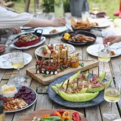 Pyszne jedzenie na stole, idealne co na grilla: owoce morza, szaszłyki, ser z orzechami i melon z szynką.