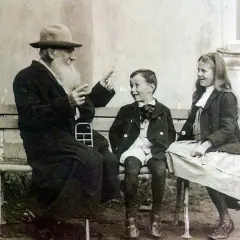 Lew Tołstoj w otoczeniu swoich dzieci, siedząc na ławce, opowiada im zapewne jakąś historię.