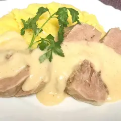 Kawałki ozorków w kremowym sosie chrzanowym, podane z purée ziemniaczanym i gałązką natki pietruszki.