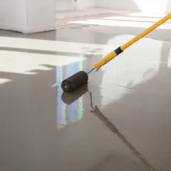Wałek do odpowietrzania wygładza świeżą wylewkę anhydrytową, przygotowując ją pod ogrzewanie podłogowe.
