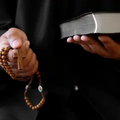 Ein Priester hält ein Rosenkranz und eine Bibel. Dies sind Werkzeuge, die bei einem Exorzismus verwendet werden, um böse Geister zu vertreiben.