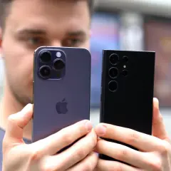 Porównanie aparatów iPhone'a i Samsunga. Który telefon ma najlepszy aparat? Dwa flagowe smartfony w dłoniach mężczyzny.