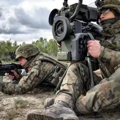 Żołnierze ćwiczą rezerwę, jeden celuje z karabinu, drugi obsługuje wyrzutnię. Poligon w tle.