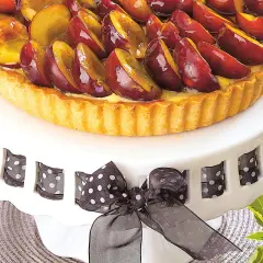 Pyszny tort ze śliwkami, z kremem śliwkowym do tortu, ozdobiony czarną wstążką w kropki.