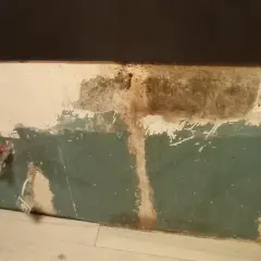 Preparazione per carteggiare muro per imbiancare: tubi rossi e impianto a vista, intonaco scrostato e macchie.