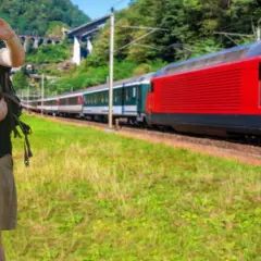 Para podróżnych z plecakami, którzy robią sobie selfie, na tle czerwonego pociągu jadącego w kierunku Krakowa Głównego i Bochni.