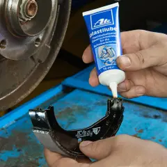 Mechanik aplikuje smar ATE Plastilube na prowadnice szczęki hamulcowej, dbając o prawidłowe działanie układu hamulcowego.