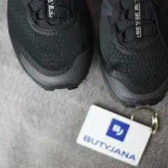 Czarne buty Salomon, model Sense Ride, z metką "BUTYJANA". Salomon to znana firma produkująca odzież i obuwie sportowe.