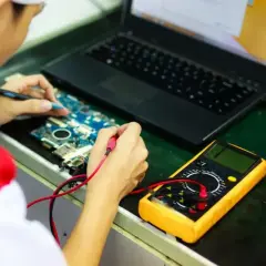 Technik elektronik bada płytę główną laptopa multimetrem. Zastanawiasz się, ile zarabia technik elektronik?