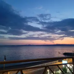 Zachód słońca nad morzem w Gaeta. Niebo w odcieniach błękitu i różu, spokojna woda, widok z tarasu.