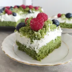 Pyszne ciasto leśny mech z mascarpone, udekorowane malinami i borówkami, wygląda jak leśna polana.