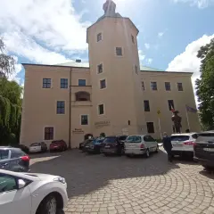 Zamek w Redzikowie, z wieżą i parkingiem przed wejściem.