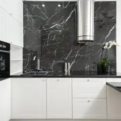 Nowoczesna kuchnia z białymi szafkami i czarnym blatem. Ściana nad blatem ozdobiona płytkami imitującymi kamień nero marquina.