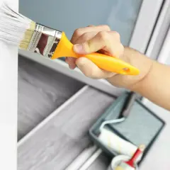 Hand streicht mit Pinsel weiße Farbe auf Kunststoffrahmen. Wetterfestes Ergebnis für Fenster und Türen.