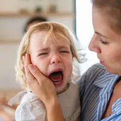 Mama pociesza płaczące dziecko, które przeżywa lęk separacyjny.