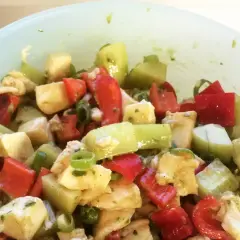 Frischer Salat mit gewürfeltem Gemüse und Käse, verfeinert mit Pesto.
