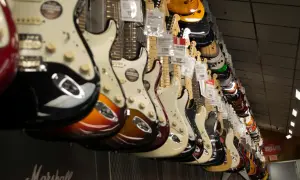 Rząd gitar elektrycznych w różnych kolorach wiszących na ścianie sklepu.