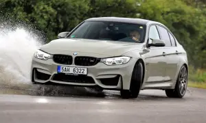 Szary BMW F80 M3 pokonuje kałużę, tworząc efektowny rozbryzg wody.