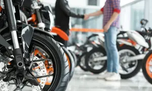 Zbliżenie na koło motocykla pcc-3 wzór. W tle dwóch mężczyzn ściska sobie dłonie na tle innych motocykli.