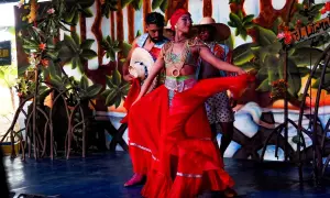 Dansare i färgglada dräkter uppträder på en scen med tropisk bakgrund, som påminner om Cali, Colombia.