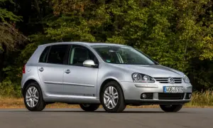 Srebrny Volkswagen Golf 5 z 2004 roku zaparkowany na drodze, z zielonym lasem w tle.
