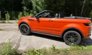 Orange Range Rover Evoque Cabrio, offen, steht auf einem Schotterweg. Mögliche Probleme mit dem Verdeck?