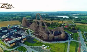 Drewniany rollercoaster Zadra w parku rozrywki, z widokiem na okoliczne pola i jeziora. Zastanawiasz się, ile jedzie Zadra?