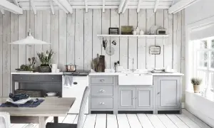 Ljust och luftigt kök med vit inredning inspiration. Träpaneler på väggar och tak, gråa skåp och en vit diskho.