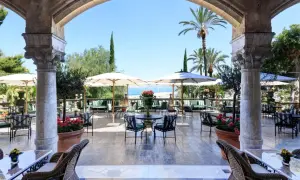 Terrazza con vista mare per un aperitivo a Palermo, tra palme e archi antichi.