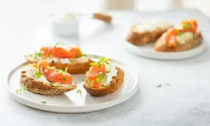 Bruschetta saumon : toasts grillés garnis de fromage frais, fines tranches de concombre, saumon fumé et herbes fraîches.