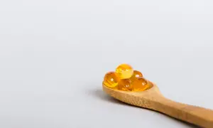 Houten lepel met gele capsules, mogelijk ter bestrijding van vitamine d tekort duizeligheid.