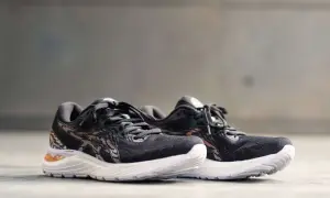 Scarpe da corsa Asics Gel Cumulus 23 nere con dettagli in bronzo e suola bianca, pronte per ogni avventura.