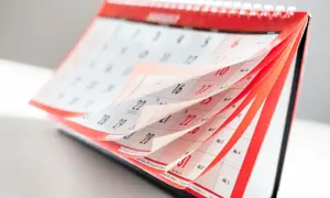 Otwarty kalendarz biurkowy z przewracanymi kartkami, widoczne daty i dni tygodnia.