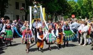 Dzieci w łowickich strojach ludowych idą w procesji Bożego Ciała. Warto uczestniczyć w procesjach Bożego Ciała w Łowiczu i okolicach, by podziwiać te barwne tradycje.