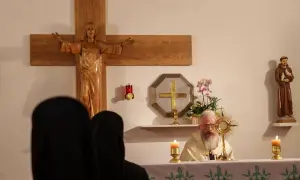 Ksiądz z brodą odprawia nabożeństwo w pierwszy czwartek miesiąca. Widać krzyż, figurę świętego i monstrancję.