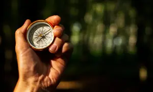 Eine Hand hält einen Kompass, der zeigt, wie funktioniert ein Kompass. Die Nadel zeigt nach Norden.
