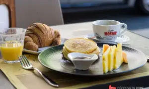 Un délicieux petit déjeuner italien : croissant, pancakes, fruits frais et café. Un régal pour bien commencer la journée !