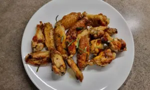 Alette di pollo in padella, dorate e succulente, guarnite con rosmarino fresco. Un piatto invitante pronto per essere gustato.