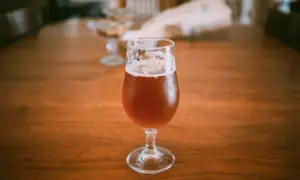 Un bicchiere di birra ambrata su un tavolo di legno. La domanda "quante birre si possono bere al giorno" aleggia nell'aria.