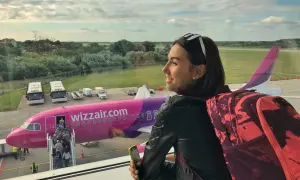 Kobieta z plecakiem patrzy na samolot Wizzair. Chcesz wiedzieć, jak zadzwonić do Wizzair za darmo? Sprawdź na stronie przewoźnika.