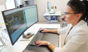 Kobieta w okularach pracuje przy komputerze, na ekranie której widoczna jest darmowa strona internetowa z ofertą konsultacji ślubnych.