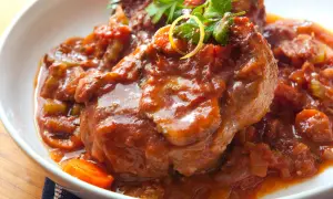 Herzhaftes Ossobuco Rezept in Tomatensoße mit Karotten und Petersilie, serviert in einer weißen Schüssel.
