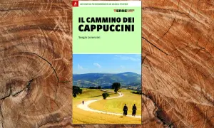 Copertina del libro "Il Cammino dei Cappuccini", con due frati che percorrono un sentiero tra colline verdi e dorate.