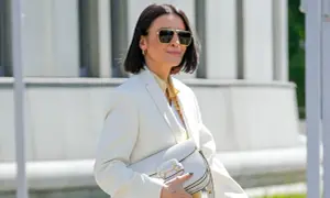 Elegancka kobieta po 50. w białej marynarce i okularach przeciwsłonecznych, z białą torebką. Stylowa moda po 50.